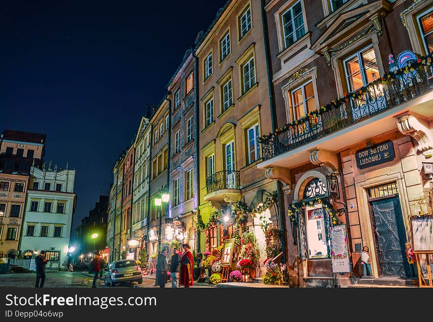 Visitors outside illuminated shops on city streets in Poland at night. Visitors outside illuminated shops on city streets in Poland at night.