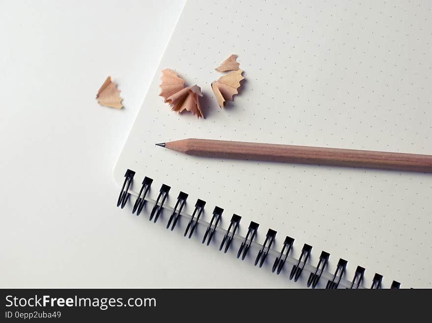 Wooden pencil with shavings on blank page of notebook. Wooden pencil with shavings on blank page of notebook.