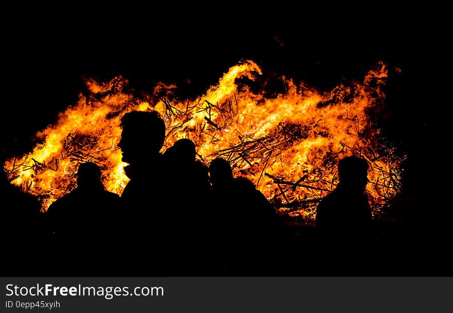 Silhouette of people outdoors next to bonfire flames. Silhouette of people outdoors next to bonfire flames.