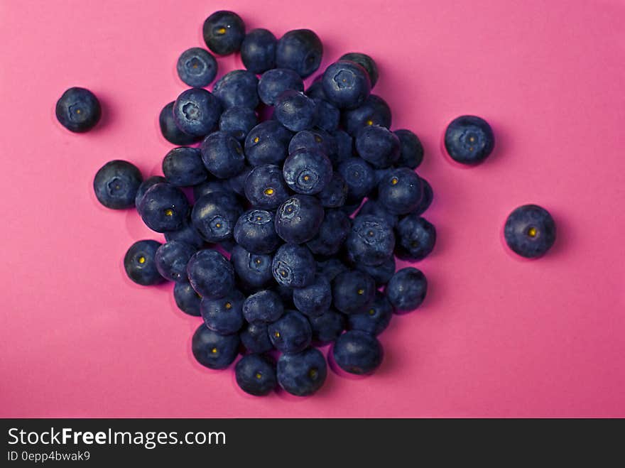 Pile of fresh whole blueberries on pink.