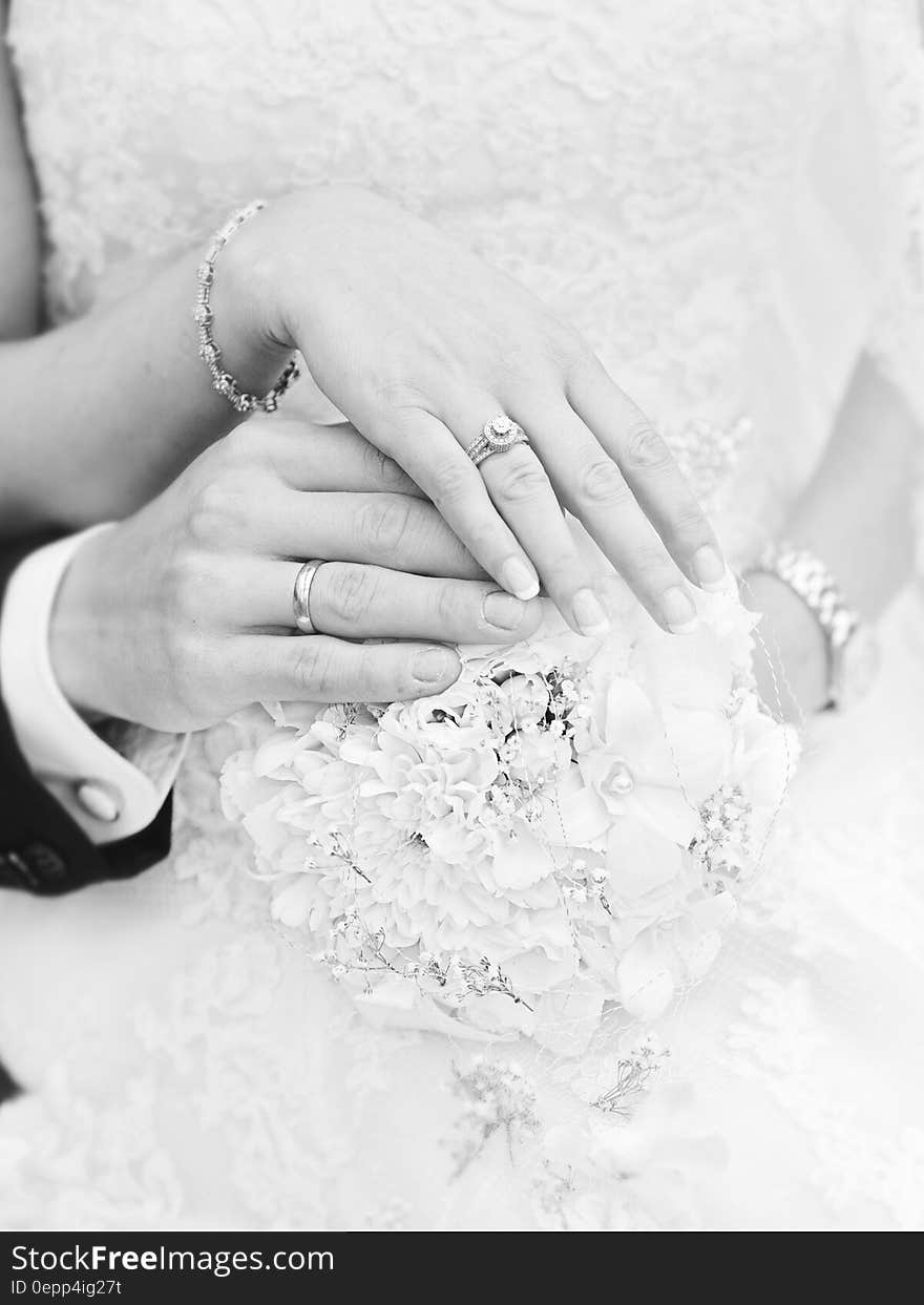 Close up on rings on hands of bride and groom in black and white.