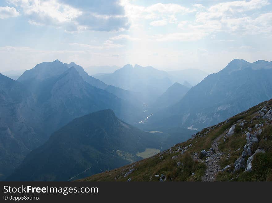 Green Grasses on Rocky Mountains Under Blue Sky