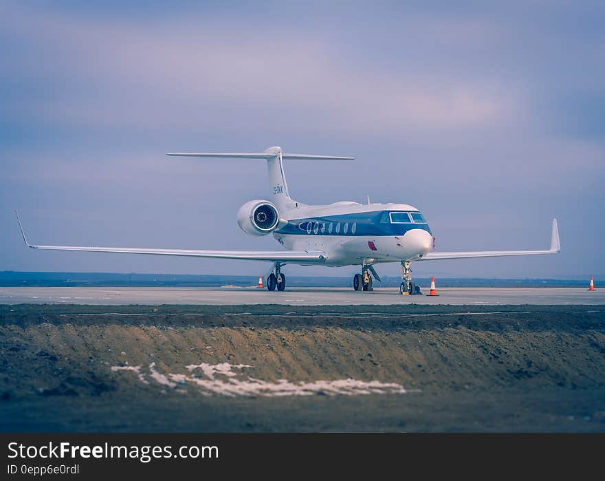 Blue and White Airplane on Concrete Ground