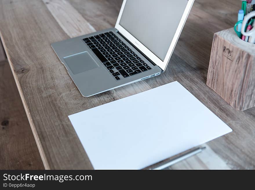 Open laptop computer with blank white papers on wooden desktop with pen. Open laptop computer with blank white papers on wooden desktop with pen.