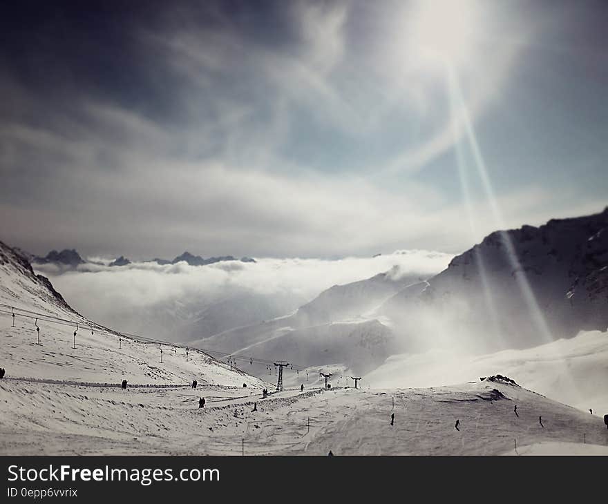 Empty snowy ski lift over slopes in mountains with sun in sky. Empty snowy ski lift over slopes in mountains with sun in sky.