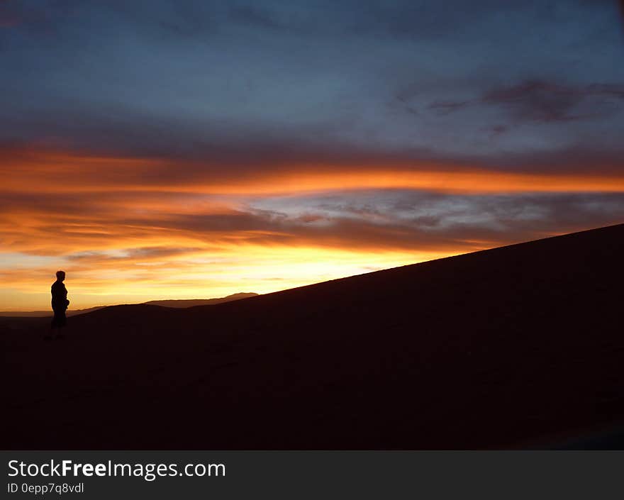 Silhouette of Person Standing Facing the Sunset