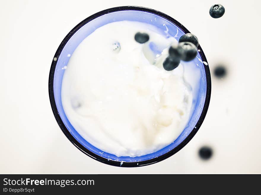 Fresh blueberries splashing into blue glass of milk. Fresh blueberries splashing into blue glass of milk.