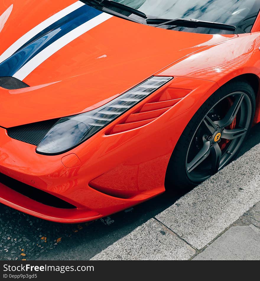 Front of orange Ferrari sports car against curb.