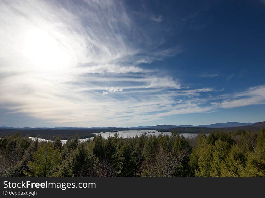 Aerial view over forest along shores of lake on sunny day. Aerial view over forest along shores of lake on sunny day.