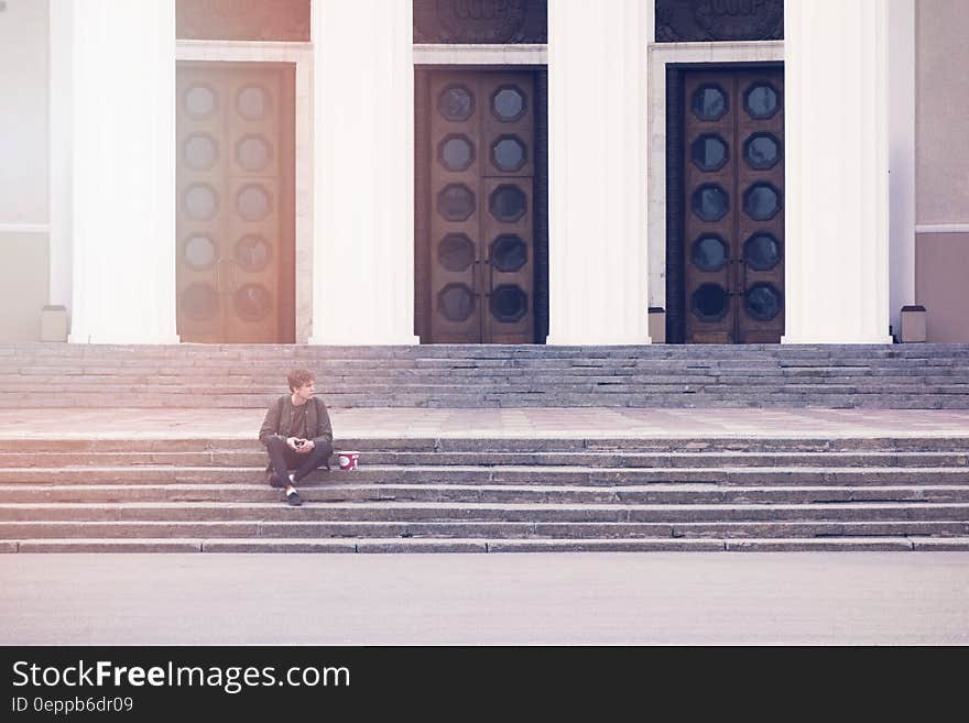 Man Sitting on a Concrete Stair Waiting for Someone during Daytime