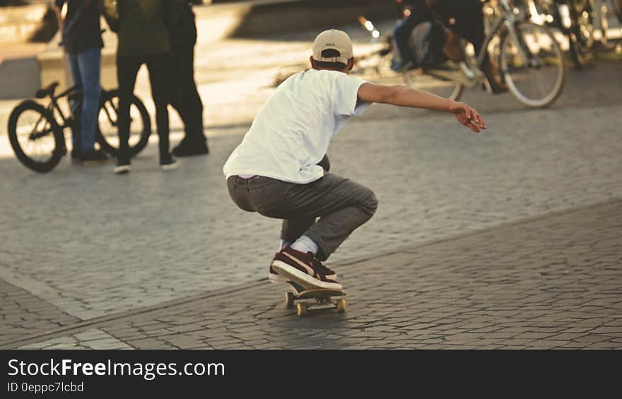 Man in White Shirt and Brown Jeans Riding Skateboard