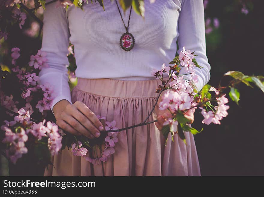 Woman Wearing White Long Sleeve Shirt and Beige Skirt Holding Pink Petaled Flower