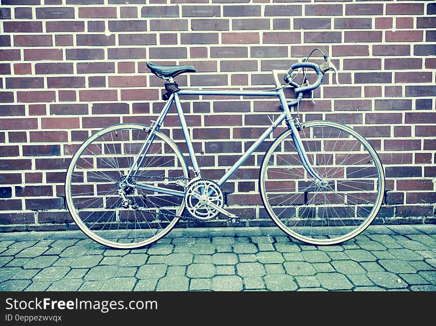 Teal and Black Road Bike Near Black and Brown Brick Wall