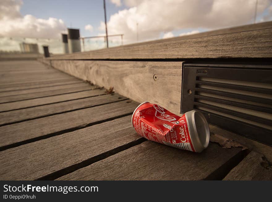 Close up of aluminum Coca-Cola can on wooden boardwalk on sunny day. Close up of aluminum Coca-Cola can on wooden boardwalk on sunny day.