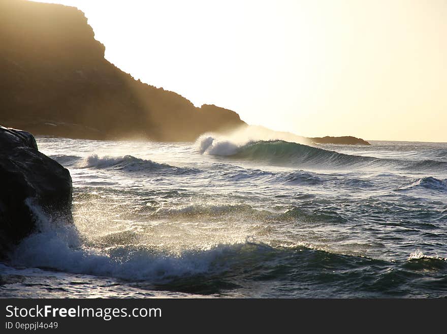 Tidal Waves Beside Mountain Slop during Daytime