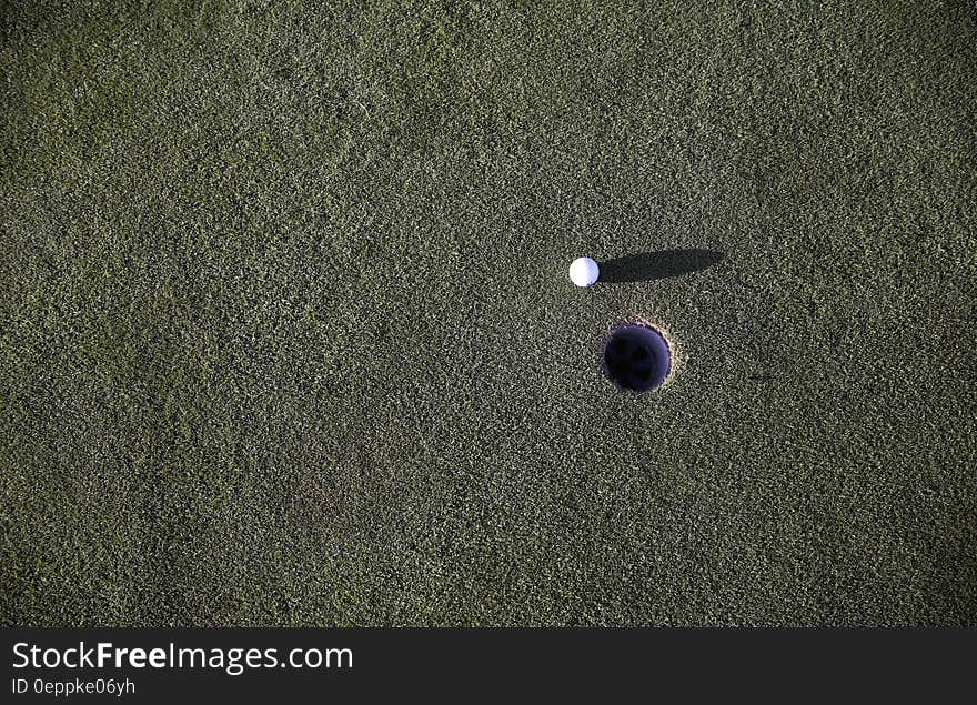 A golf ball next to the hole on a golf course. A golf ball next to the hole on a golf course.