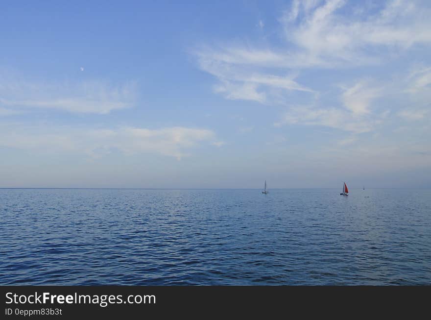 Small yachts sailing on calm blue sea with cloudscape background. Small yachts sailing on calm blue sea with cloudscape background.