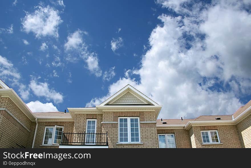 Brown Bricked House Under Cloudy Skies