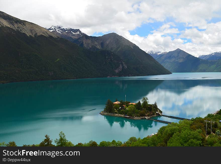 Green Small Island Sorrounded by Bodies of Water Under Cloudy Sky