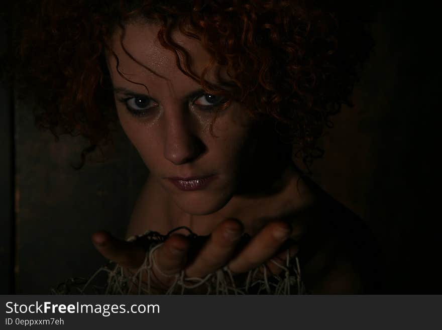 Portrait of woman in shadows holding netting in open palms.