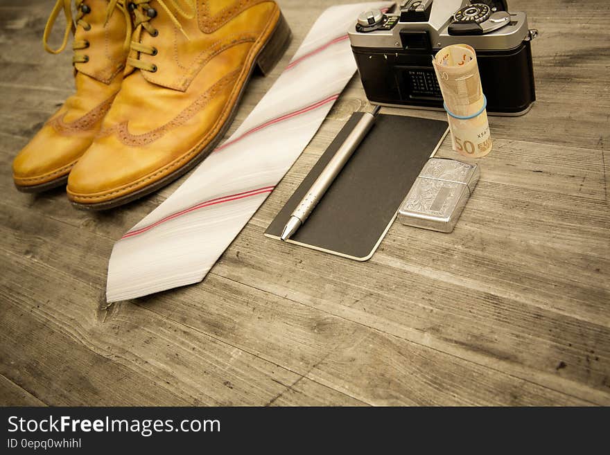 Brown Leather Oxford Wingtip Shoes Beside White and Pink Necktie on Brown Wooden Table