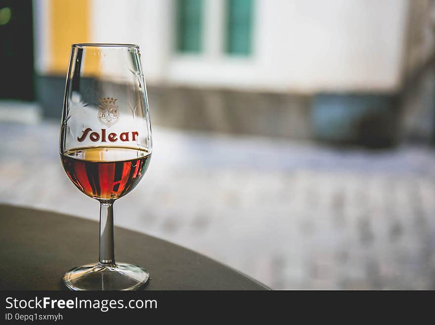 Close up of glass of liquor on table inside cafe on sunny day.