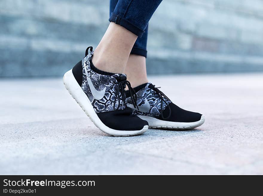 Close up of woman wearing Nike sneakers on feet outdoors on pavement. Close up of woman wearing Nike sneakers on feet outdoors on pavement.