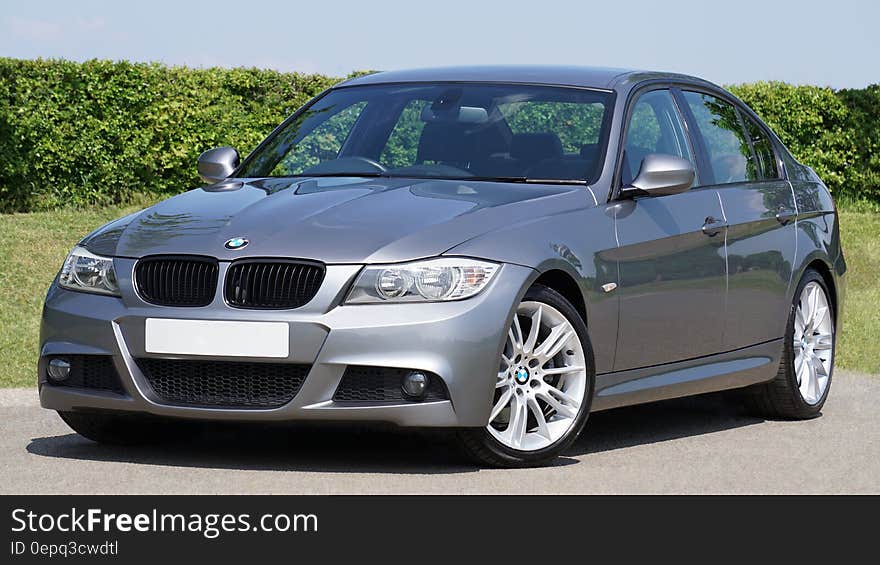 Luxury car, a German made BMW Series 3 saloon in silver with alloy wheels, green garden background. Luxury car, a German made BMW Series 3 saloon in silver with alloy wheels, green garden background.