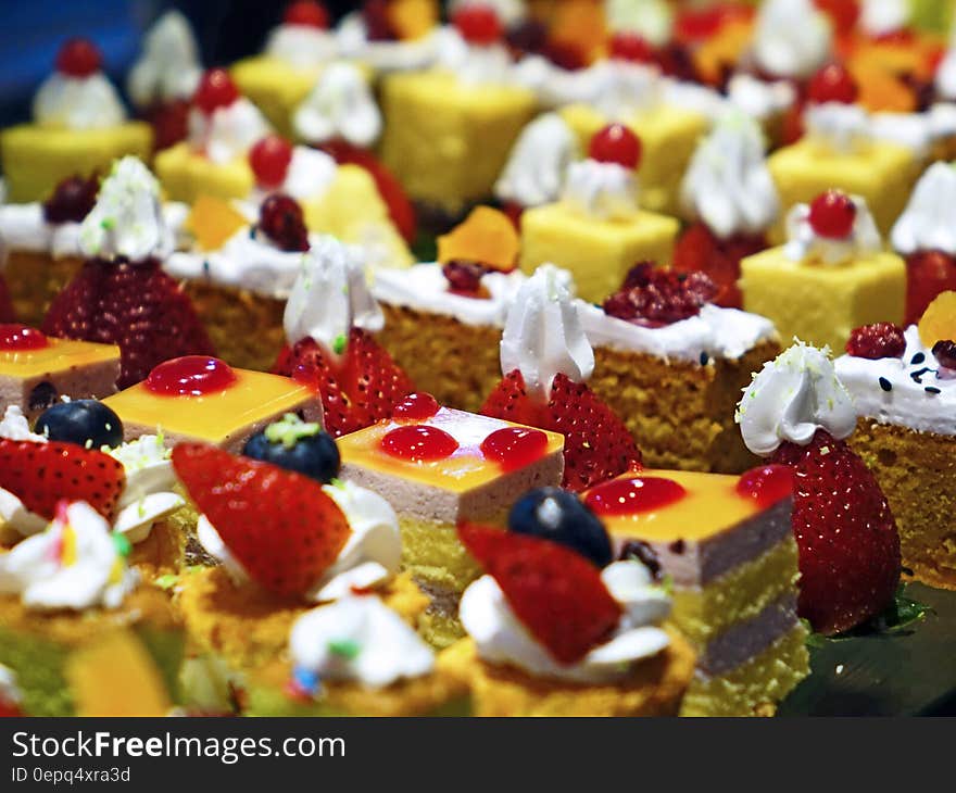 A bunch of small cakes with fruits and cream for serving. A bunch of small cakes with fruits and cream for serving.