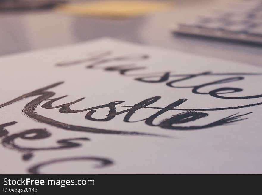 A hand-written calligraphy text of the word "hustle" on white paper. A hand-written calligraphy text of the word "hustle" on white paper.