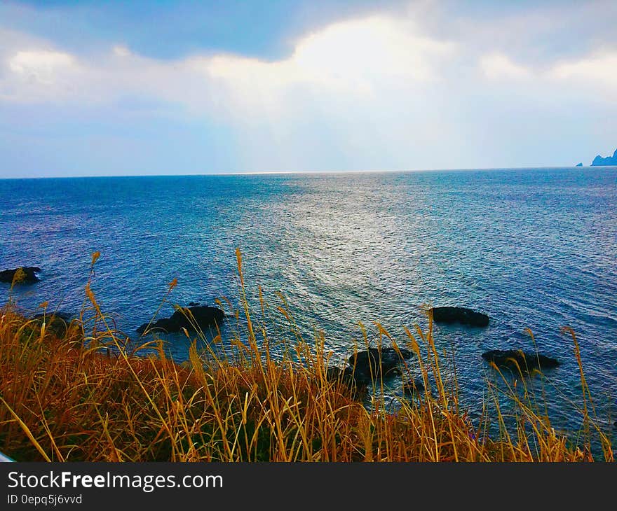 Stones in Sea Under Gray Sky During Daytime