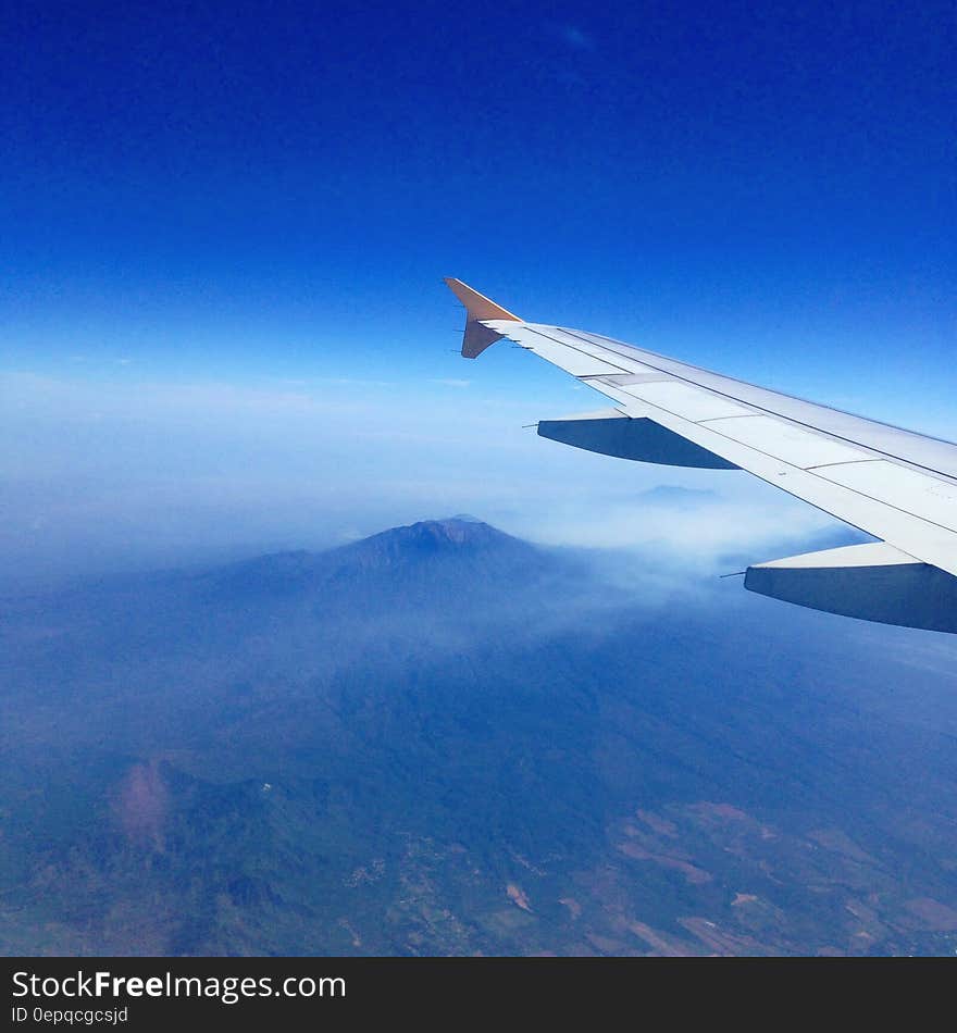 Wing of airplane in blue skies over mountains. Wing of airplane in blue skies over mountains.