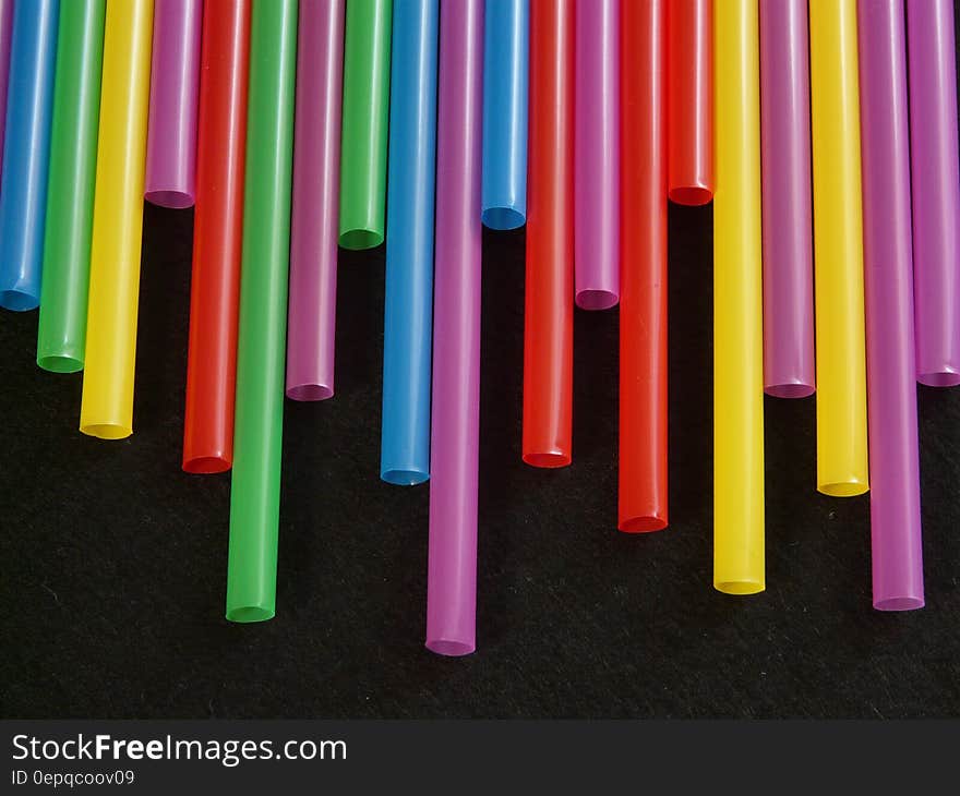 Close up of uneven line of colorful drinking straws on black.