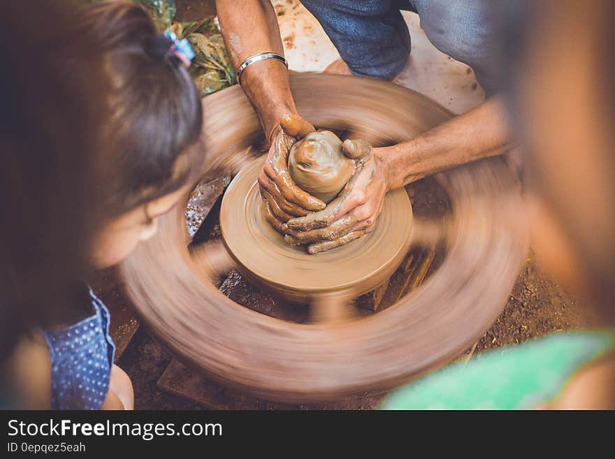 Person Making Clay Pot in Front of Girl during Daytime