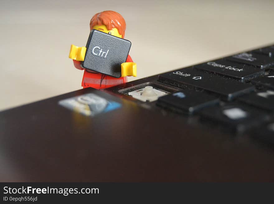 A toy man removing a computer keyboard key. A toy man removing a computer keyboard key.