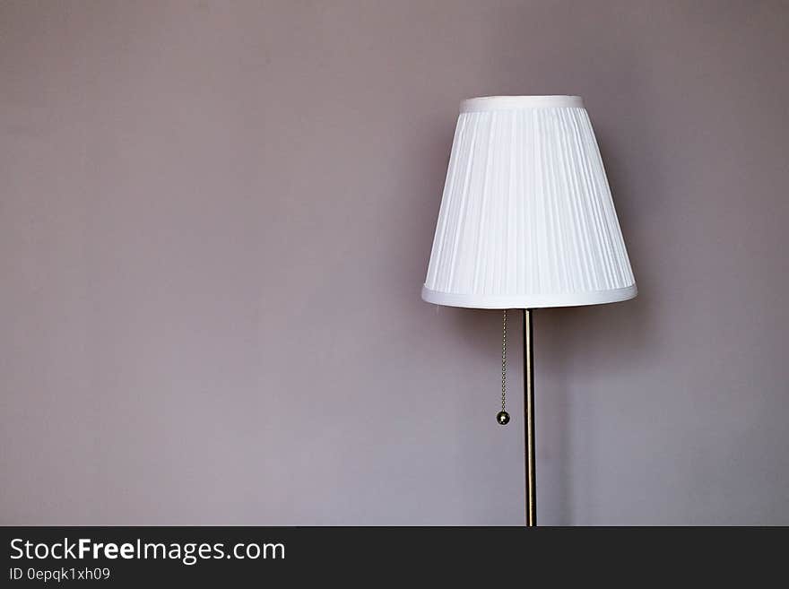 White and Grey Metal Pedestal Lamp Nearby Grey Painted Wall