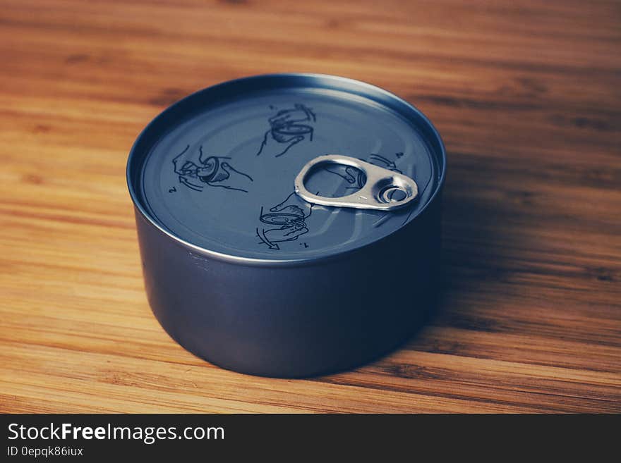 A close up shot of a gray tin can on a wooden table. A close up shot of a gray tin can on a wooden table.