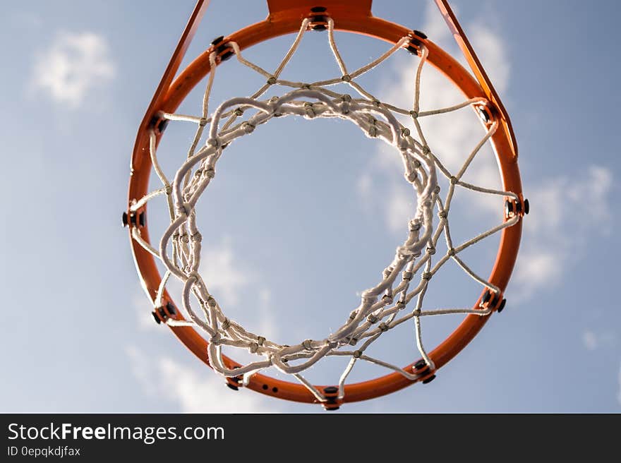 A close up shot of a red basketball basket and blue sky in the background.