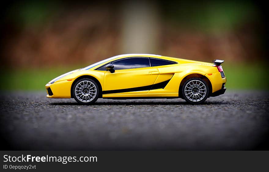 A yellow toy Lamborghini car on asphalt.