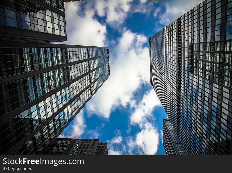 Facade of mirrored modern skyscrapers against blue skies with clouds. Facade of mirrored modern skyscrapers against blue skies with clouds.