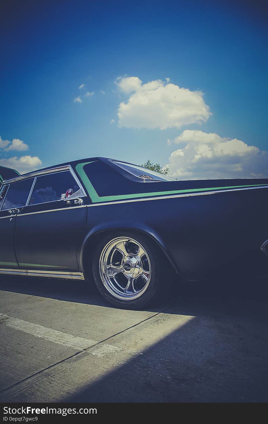 Classic car on streets against blue skies on sunny day.