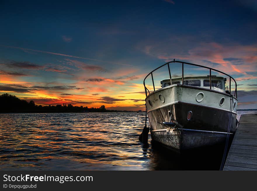 Boat moored in water at sunset over lake. Boat moored in water at sunset over lake.