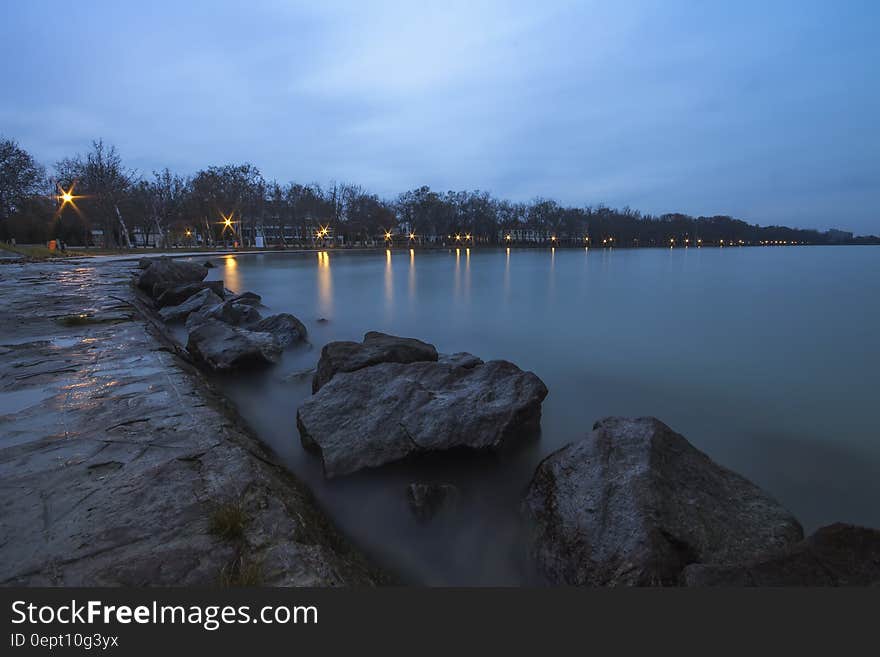 Large Rocks in Bay Under White and Blue Cloudy Sky