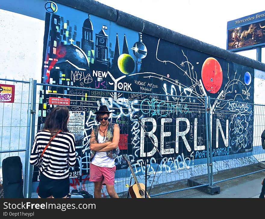 Man Wearing Black Waistcoat and White Tank Tops Standing Near a Mural