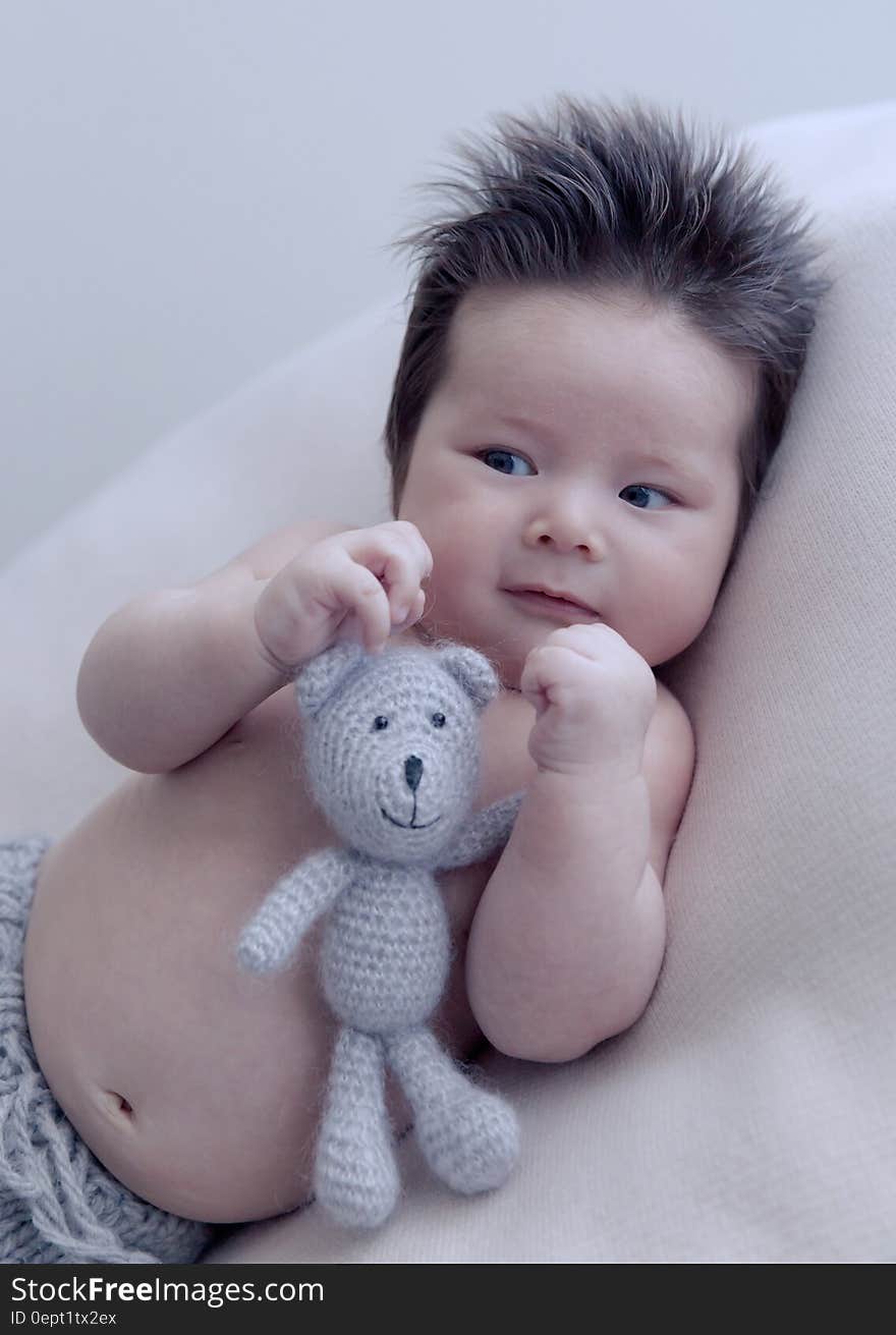 Portrait of Asian baby with crochet doll on white pillow. Portrait of Asian baby with crochet doll on white pillow.