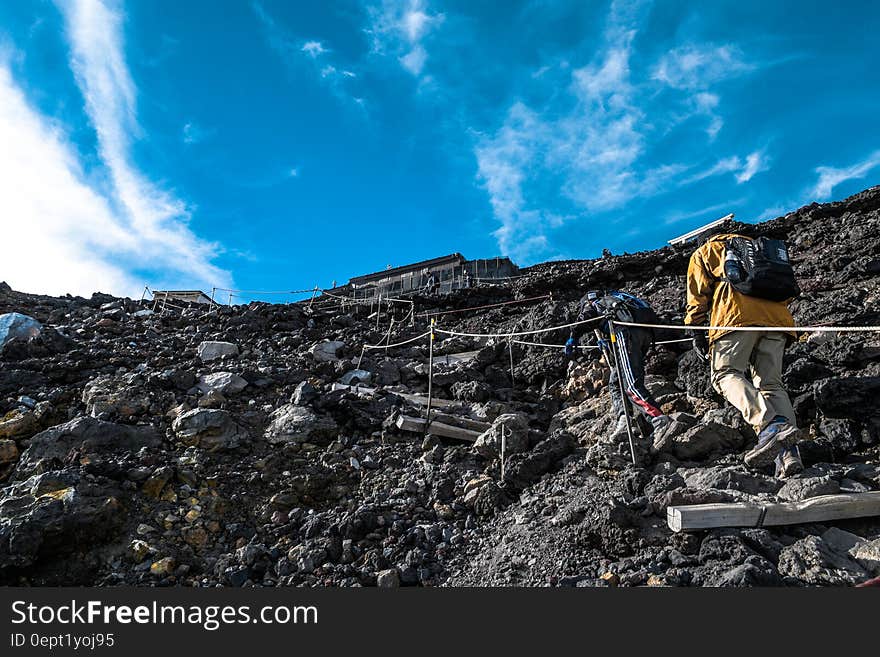 Hikers using ropes to ascend mountain on sunny day. Hikers using ropes to ascend mountain on sunny day.