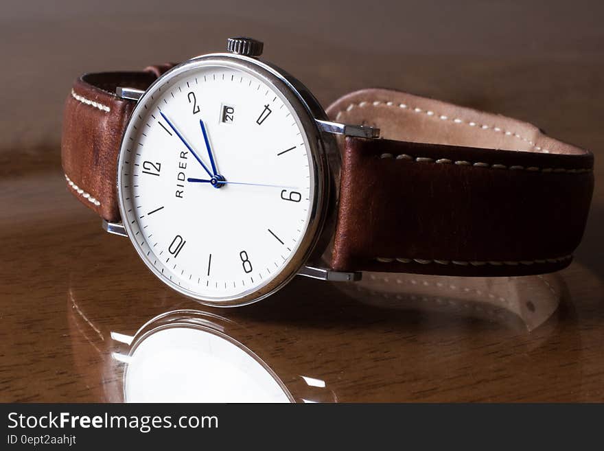 Wristwatch with leather band reflecting on glass tabletop. Wristwatch with leather band reflecting on glass tabletop.