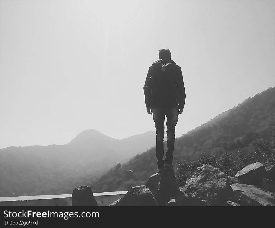 Back of man standing on boulder on mountain side with fog in black and white. Back of man standing on boulder on mountain side with fog in black and white.