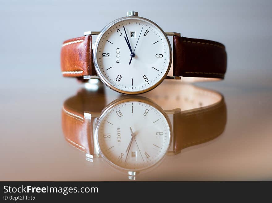 Close up of vintage Rider wristwatch with brown leather band reflecting on glass tabletop. Close up of vintage Rider wristwatch with brown leather band reflecting on glass tabletop.