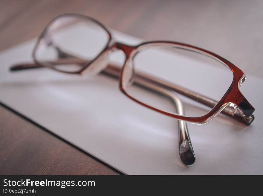 Eyeglasses on blank sheet of paper on wooden tabletop. Eyeglasses on blank sheet of paper on wooden tabletop.